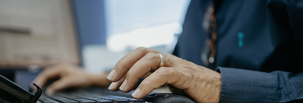 Profissional digitando em notebook durante análise de dados para inventário patrimonial em ambiente de escritório