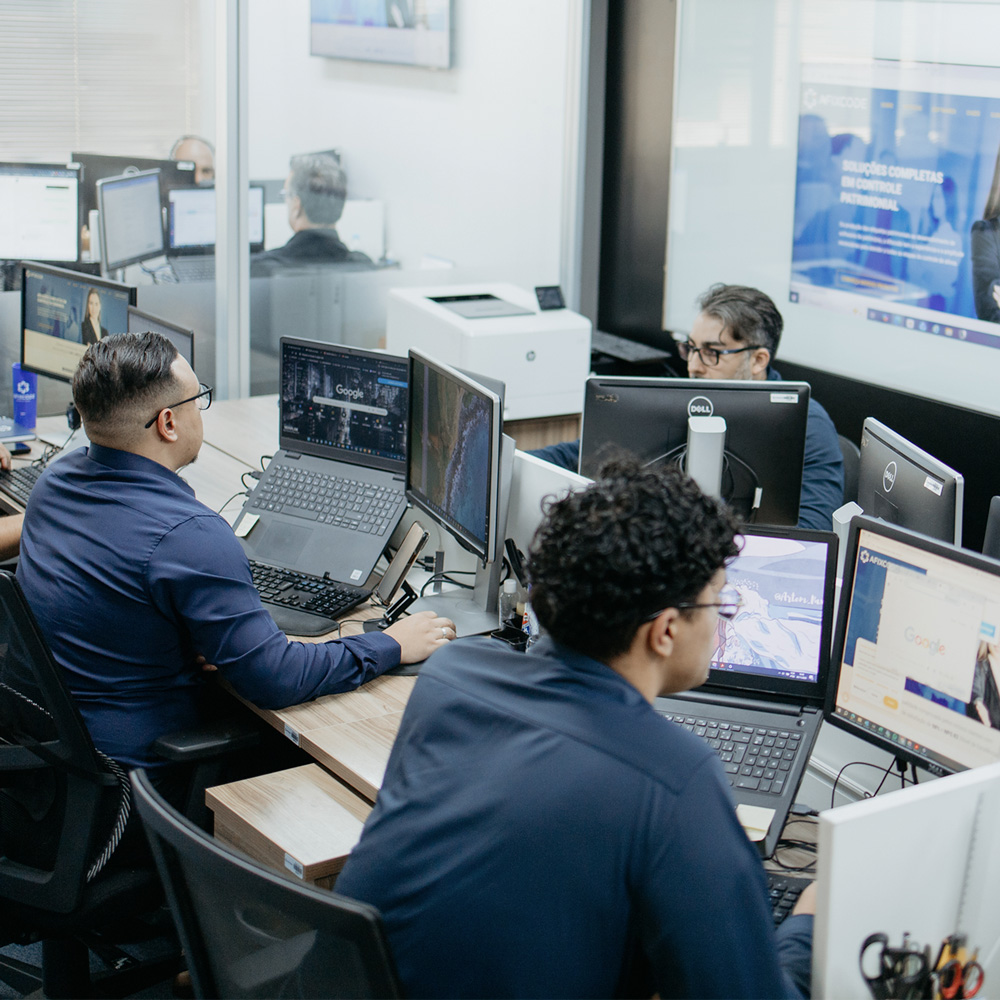 Equipe trabalhando em computadores no escritório da Afixcode com sistemas abertos para projetos de patrimônio e avaliação
