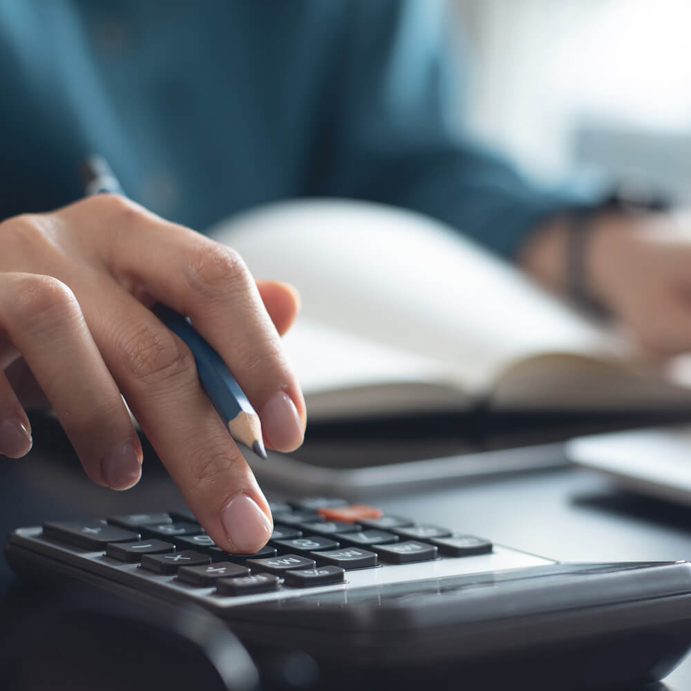 Profissional realizando cálculos em calculadora durante análise financeira para avaliação patrimonial para fins de seguros