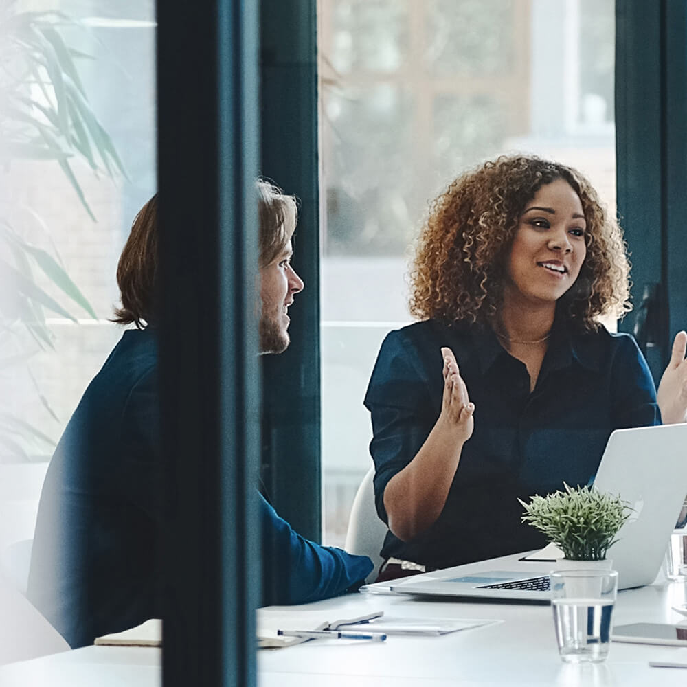 Profissionais em reunião com notebook discutindo processos de gestão do ativo imobilizado em ambiente corporativo