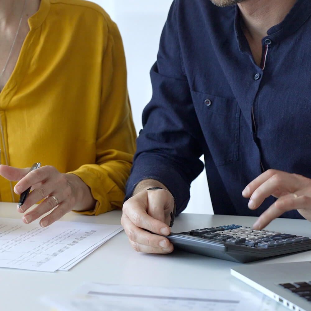 Profissionais analisando documentos e calculadora durante levantamento de créditos do ICMS