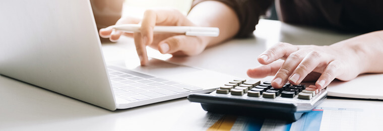 Profissional utilizando calculadora e notebook para cálculo da depreciação dos ativos imobilizados em análise financeira